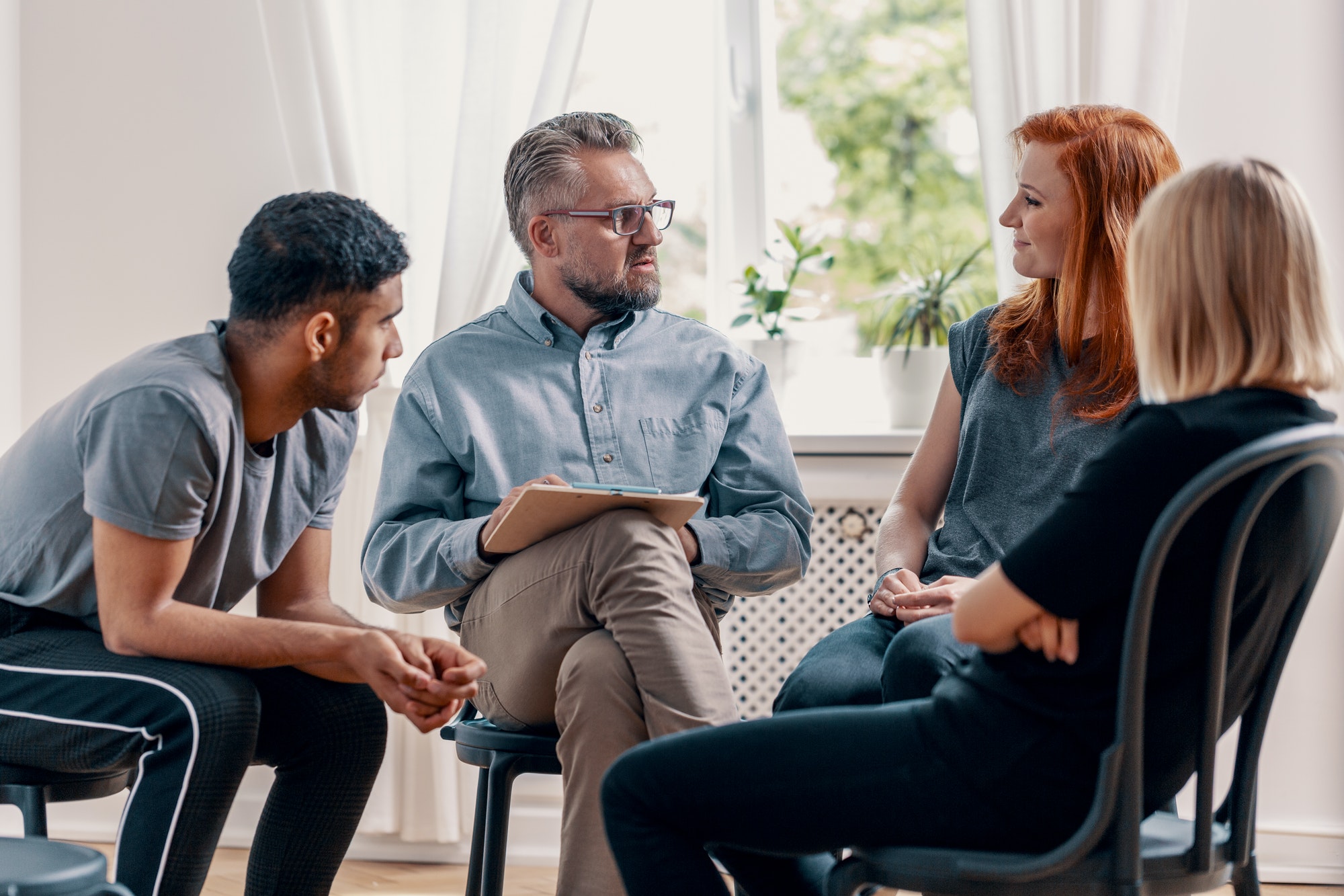 counselor talking to his patients during treatment in an office.