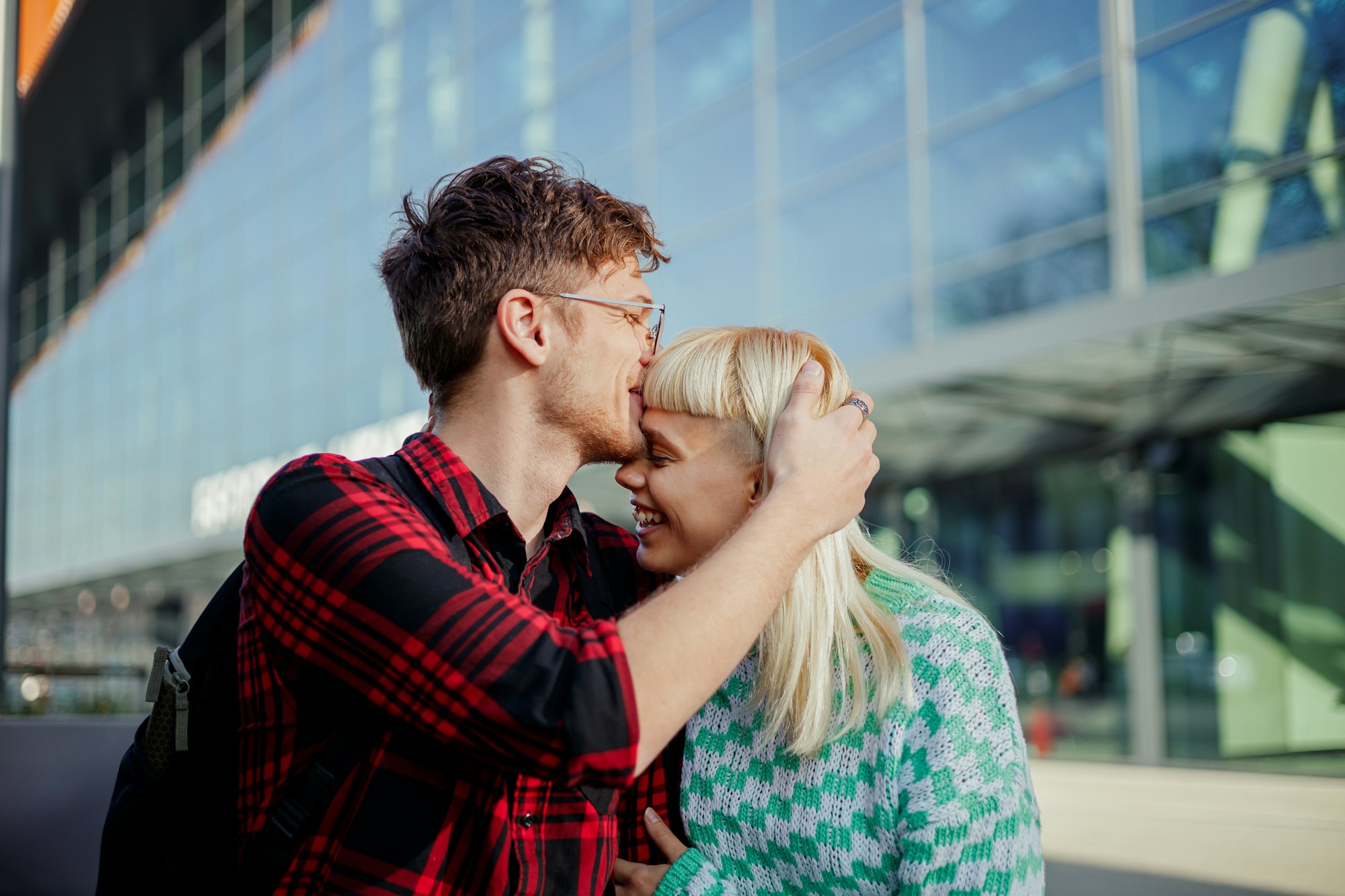 A couple in love is kissing on a city street downtown.