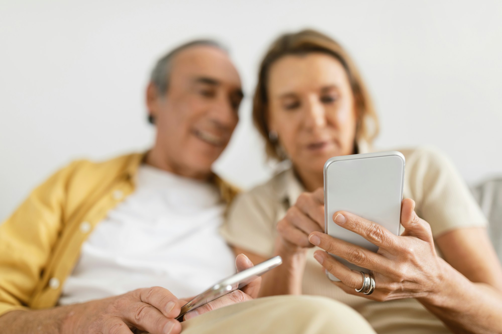 Married senior couple using smartphones, trying to understand mobile application, surfing internet